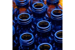Image close-up of empty blue glass bottles with open necks, recyclable packaging and beverage industry concept